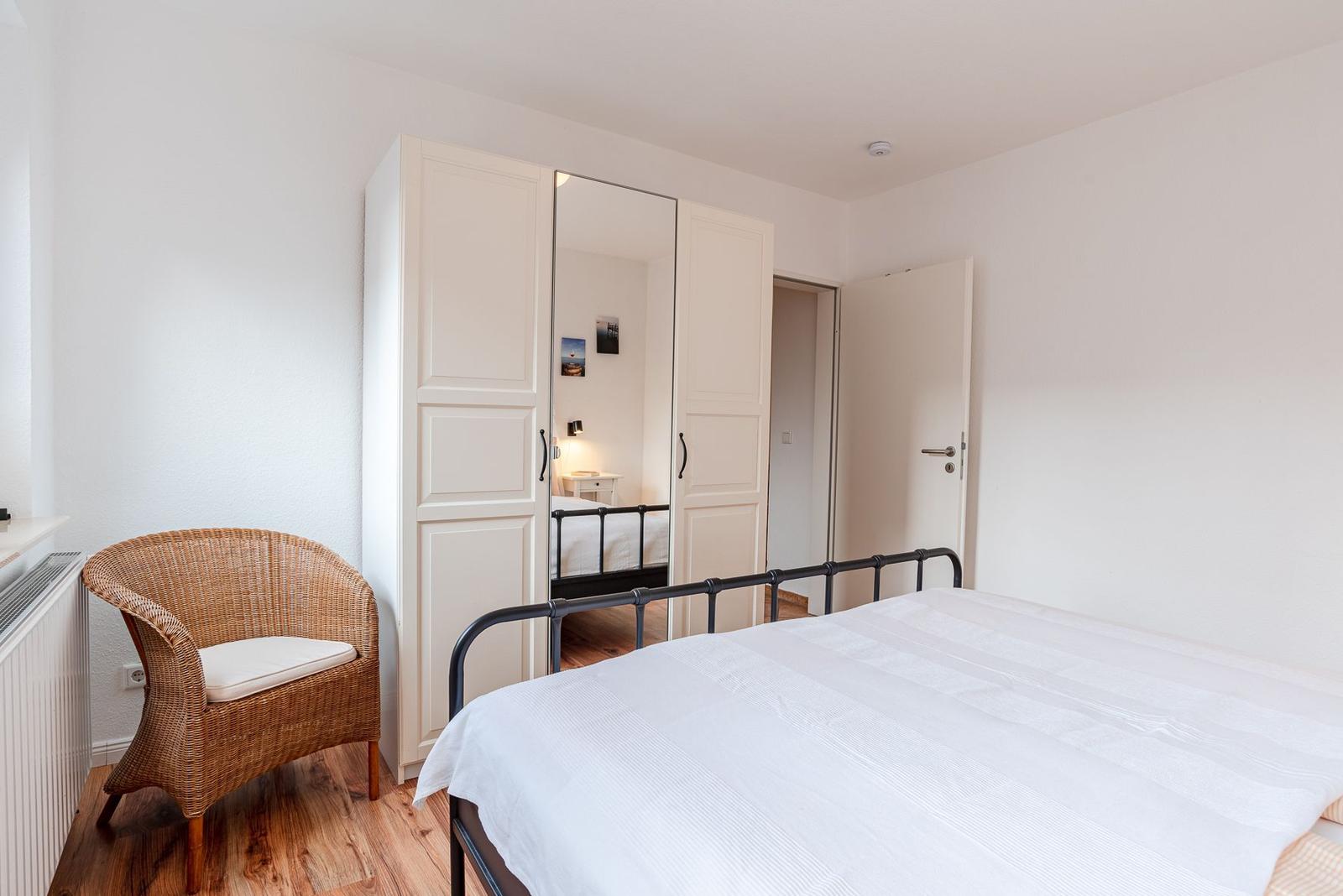 Schlafzimmer mit Bett, Kleiderschrank und Stuhl.