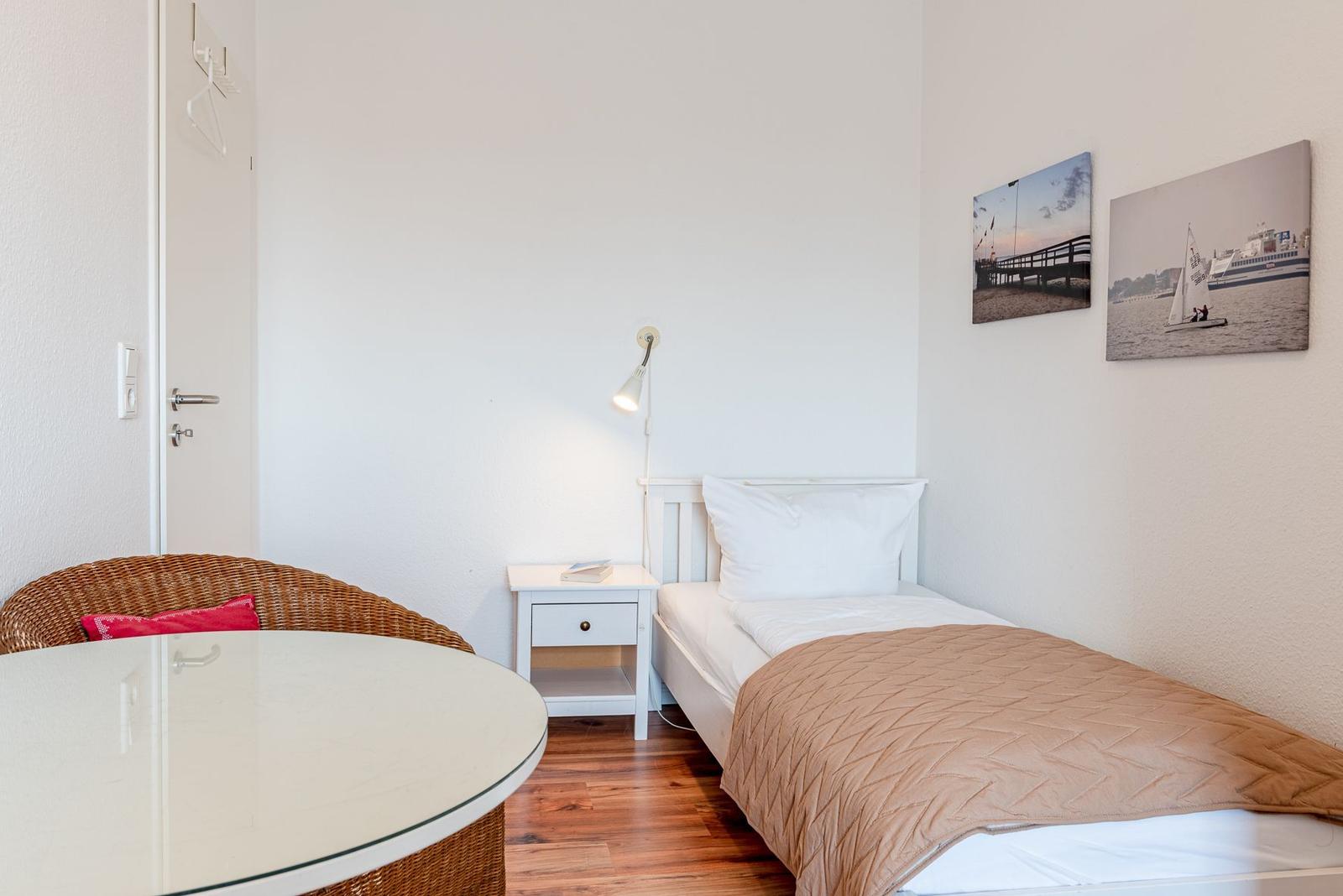 Ein Schlafzimmer mit Einzelbett, Nachttisch, Wandlampen und zwei Wandbildern.