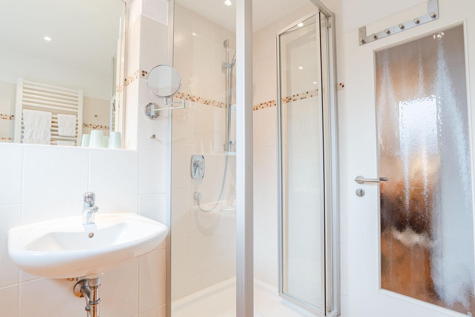 Badezimmer mit Dusche, Waschbecken und Spiegel
