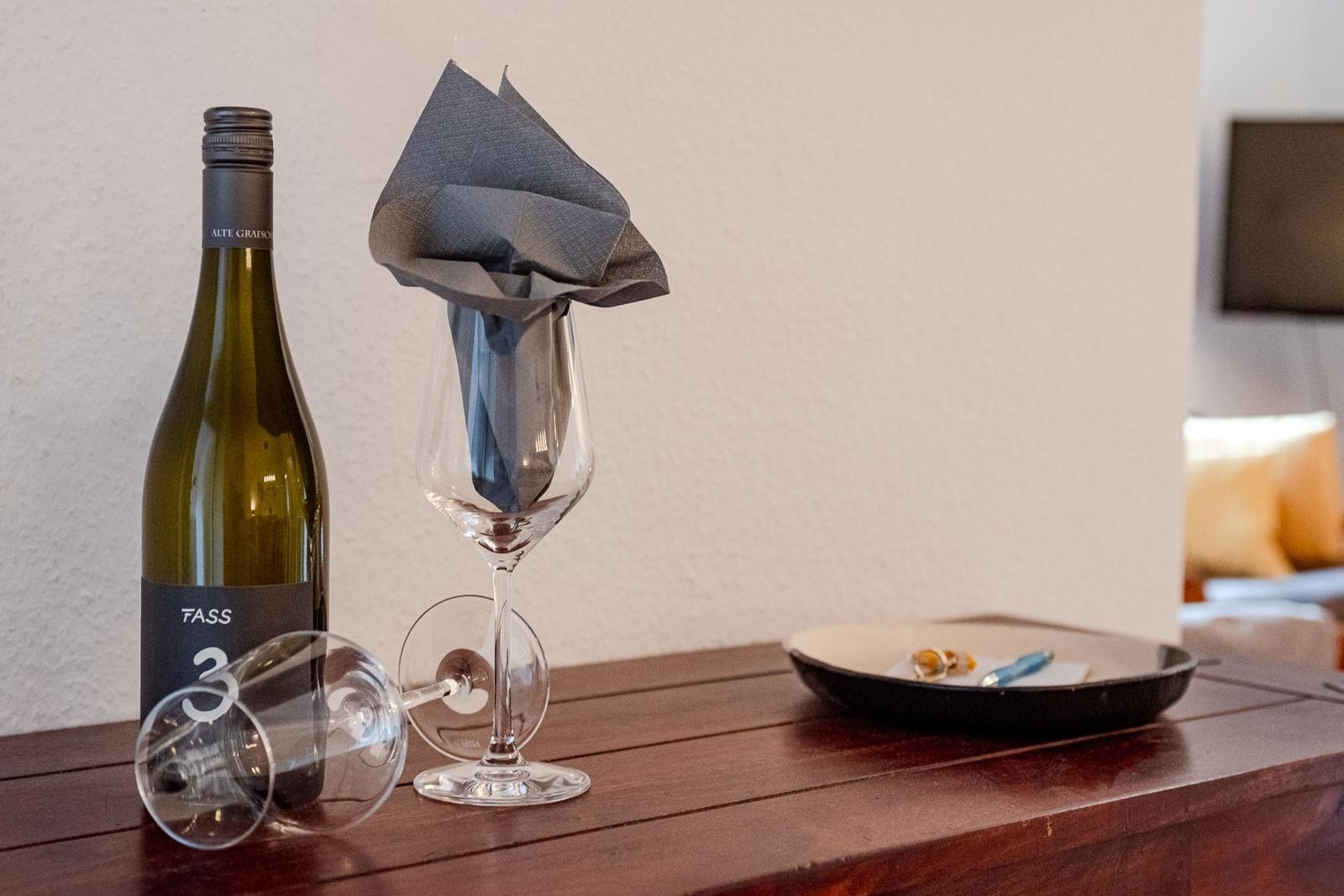 Eine Flasche Weißwein und zwei Gläser auf einem Holztisch.
