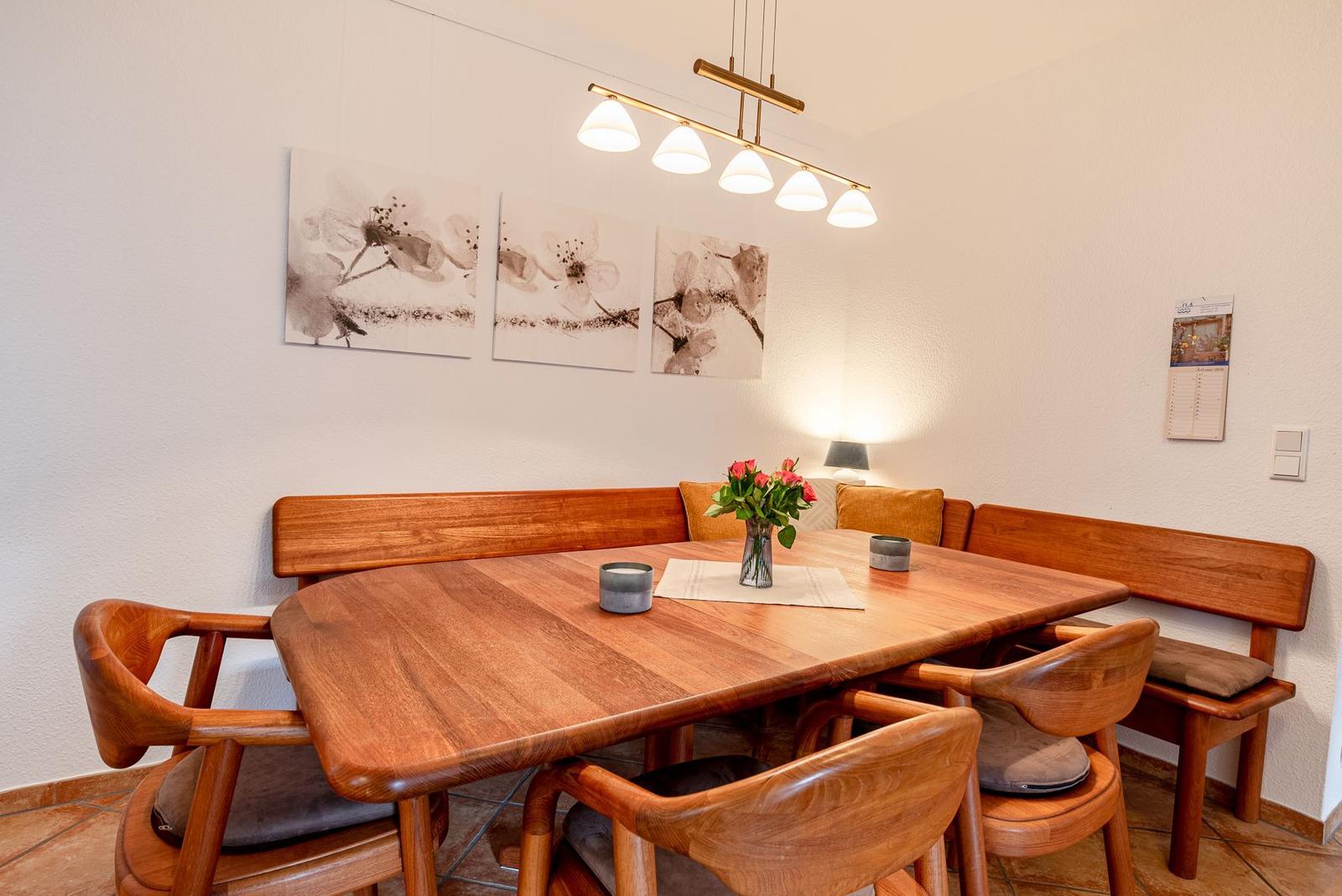 Esszimmer mit Holztisch, Bänken und Stühlen. Wandbild und Deckenleuchte.