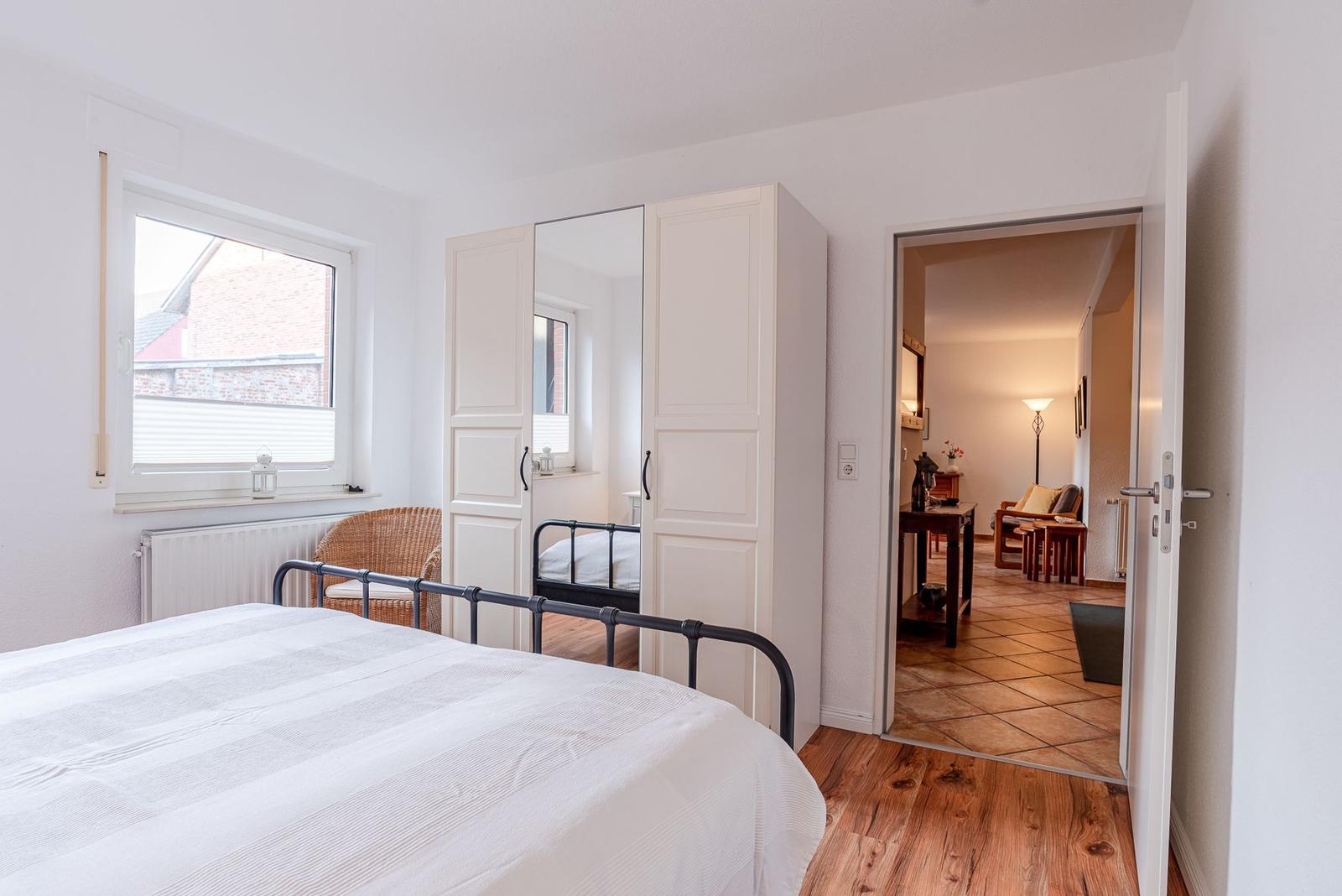 Schlafzimmer mit Bett, Kleiderschrank und Blick in Wohnbereich.