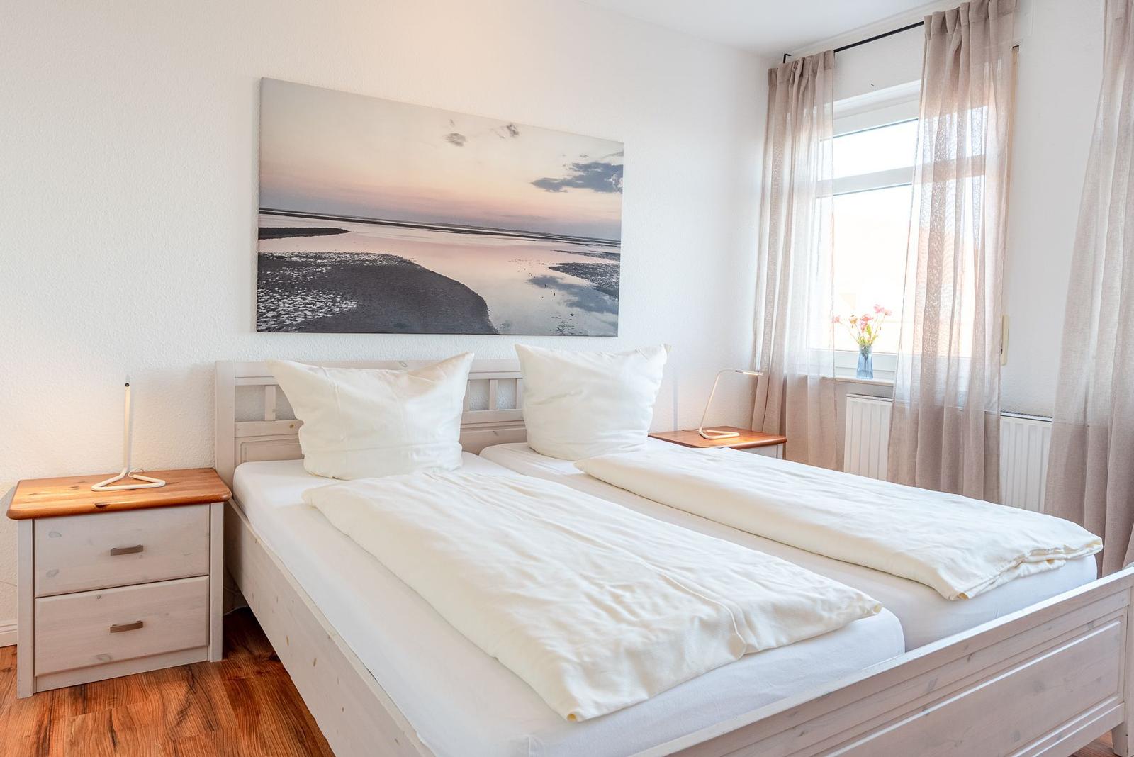 Ein Schlafzimmer mit einem Doppelbett, zwei Nachttischen und einem Fenster mit Vorhängen.