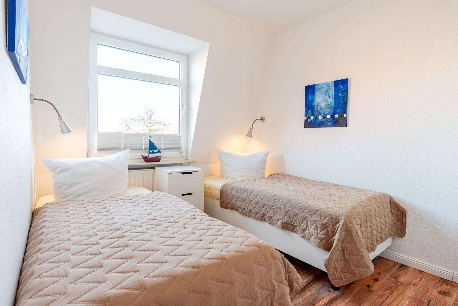 Zwei Einzelbetten mit braunen Decken, Fenster mit Segelboot und Wandbild.