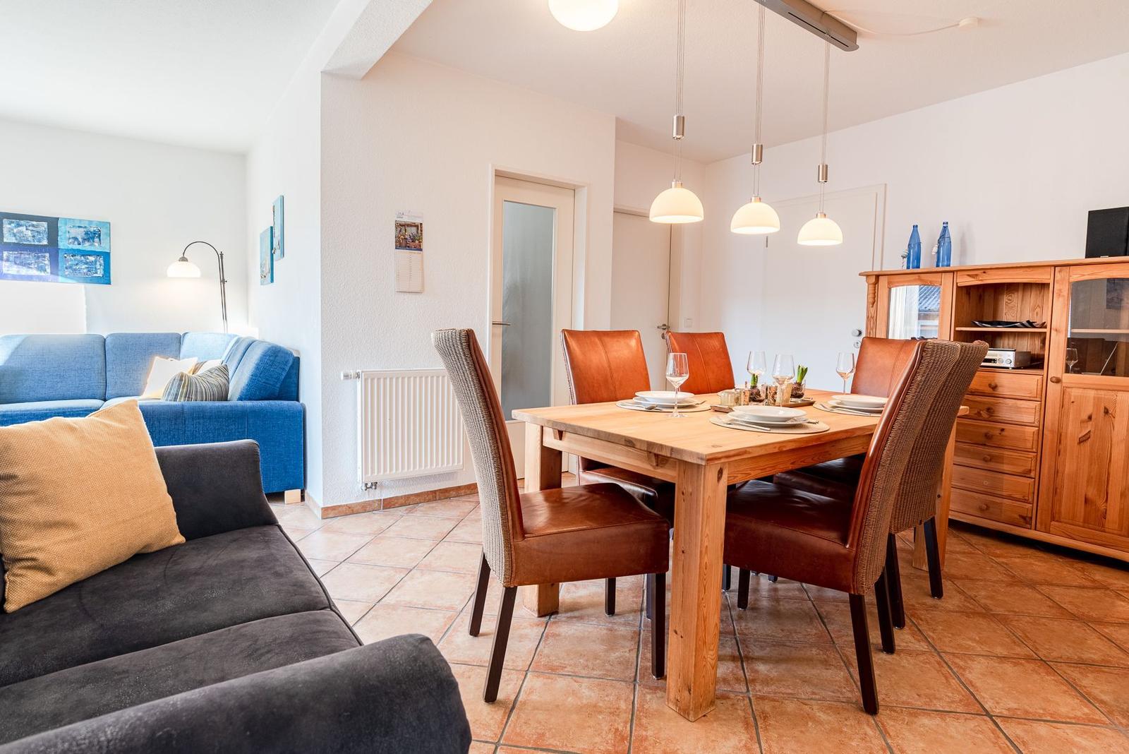 Essbereich mit Holztisch und Stühlen, daneben Wohnbereich mit Sofa und Couch.