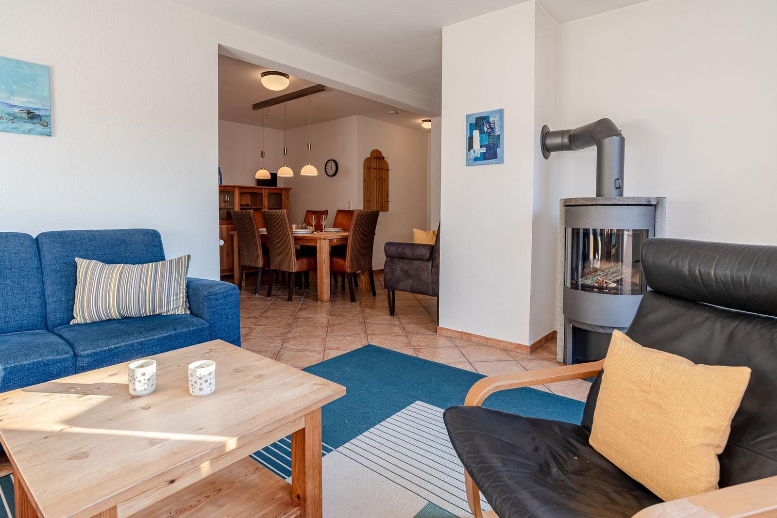 Wohnzimmer mit Sofa, Sessel und Kamin. Essbereich im Hintergrund.