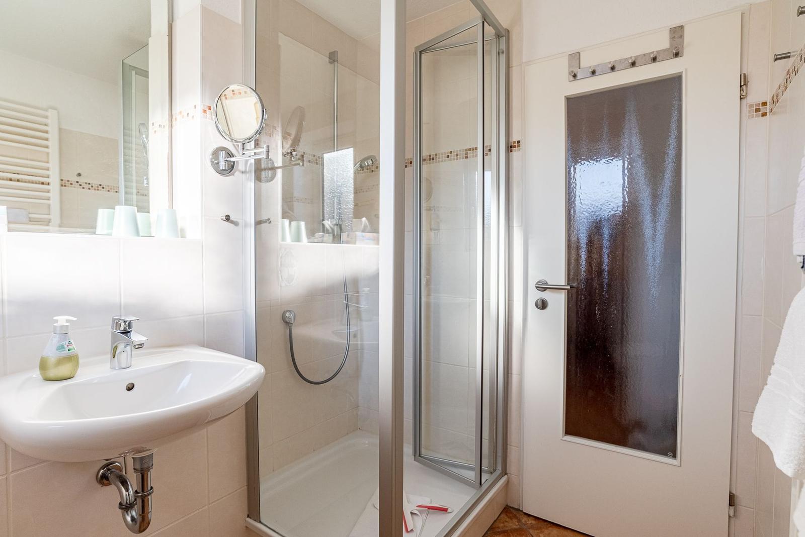 Badezimmer mit Dusche, Waschbecken und Spiegel