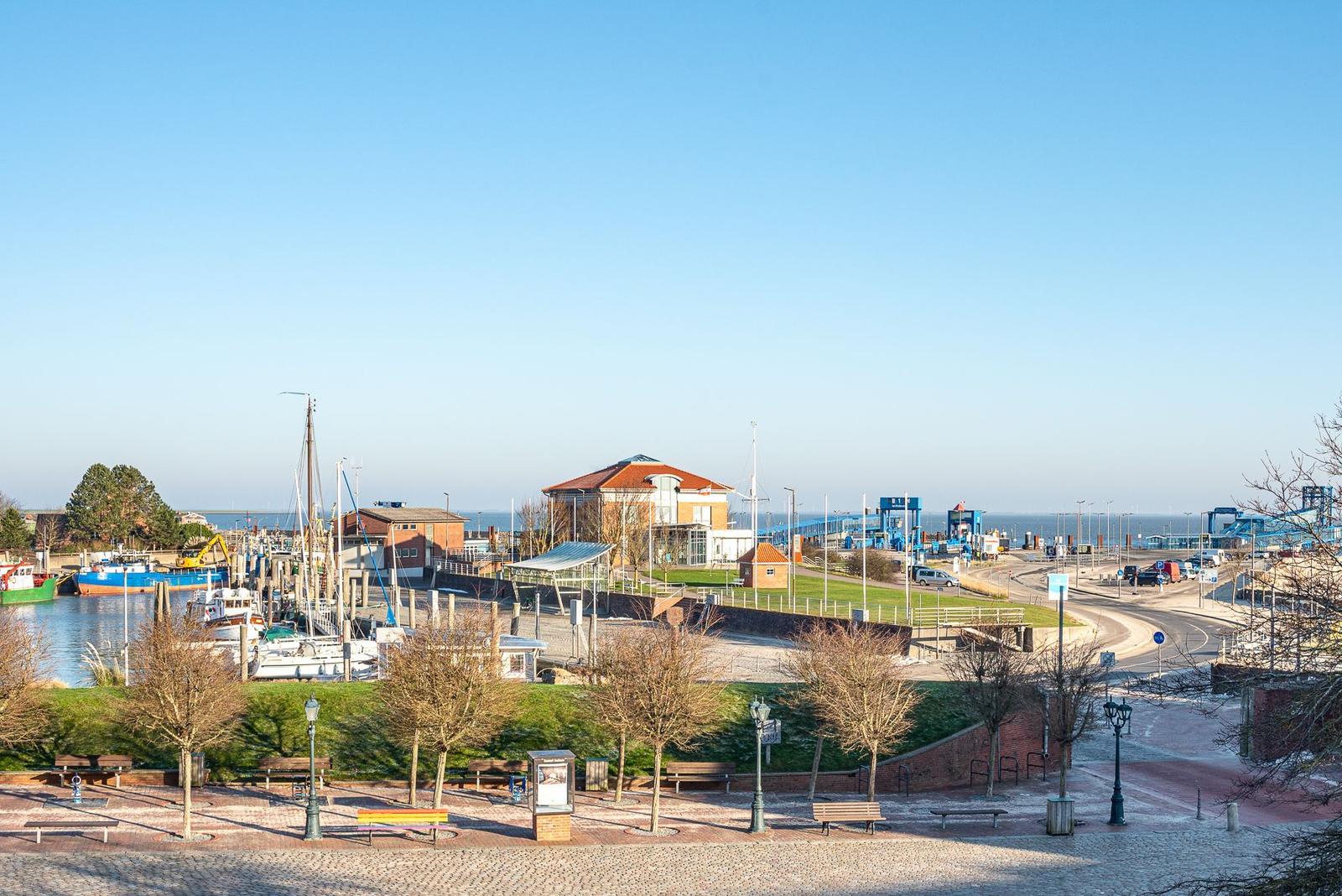 Hafen mit Booten, Grünflächen und modernen Gebäuden unter klarem Himmel.