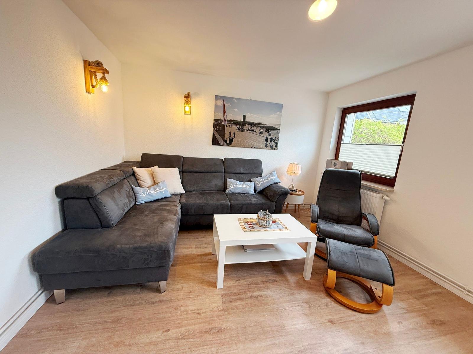 Wohnzimmer mit grauem Sofa, weißem Couchtisch und schwarzem Sessel.