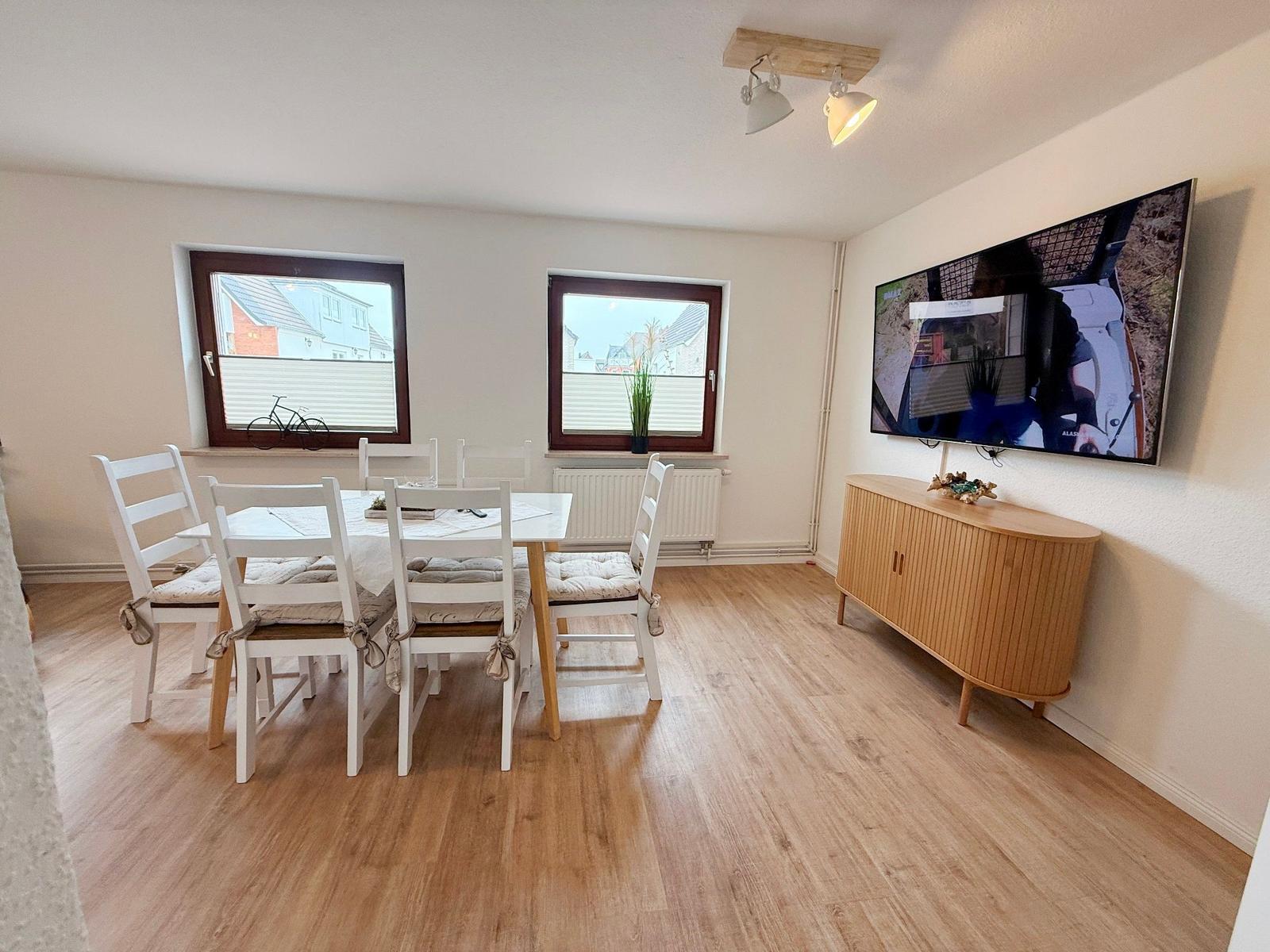 Esszimmer mit Tisch, Stühlen und TV an der Wand.