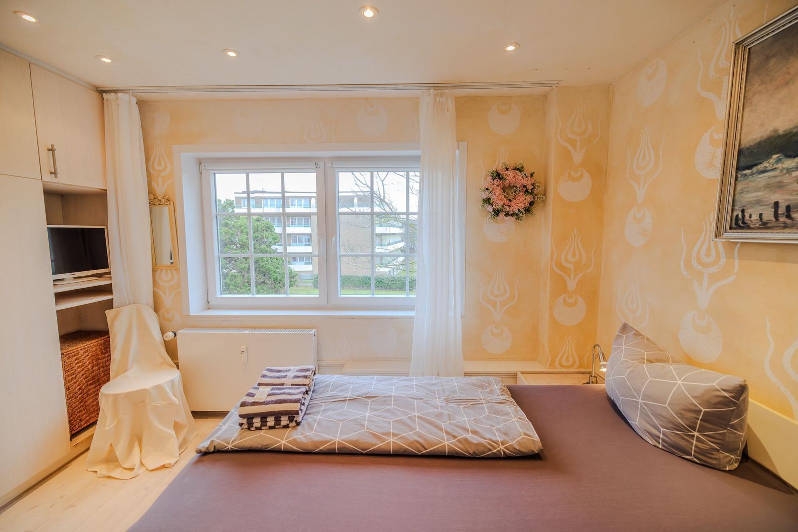 Schlafzimmer mit Bett, Fenster, Wandbild und Schrank. Wandtapete mit Muster.