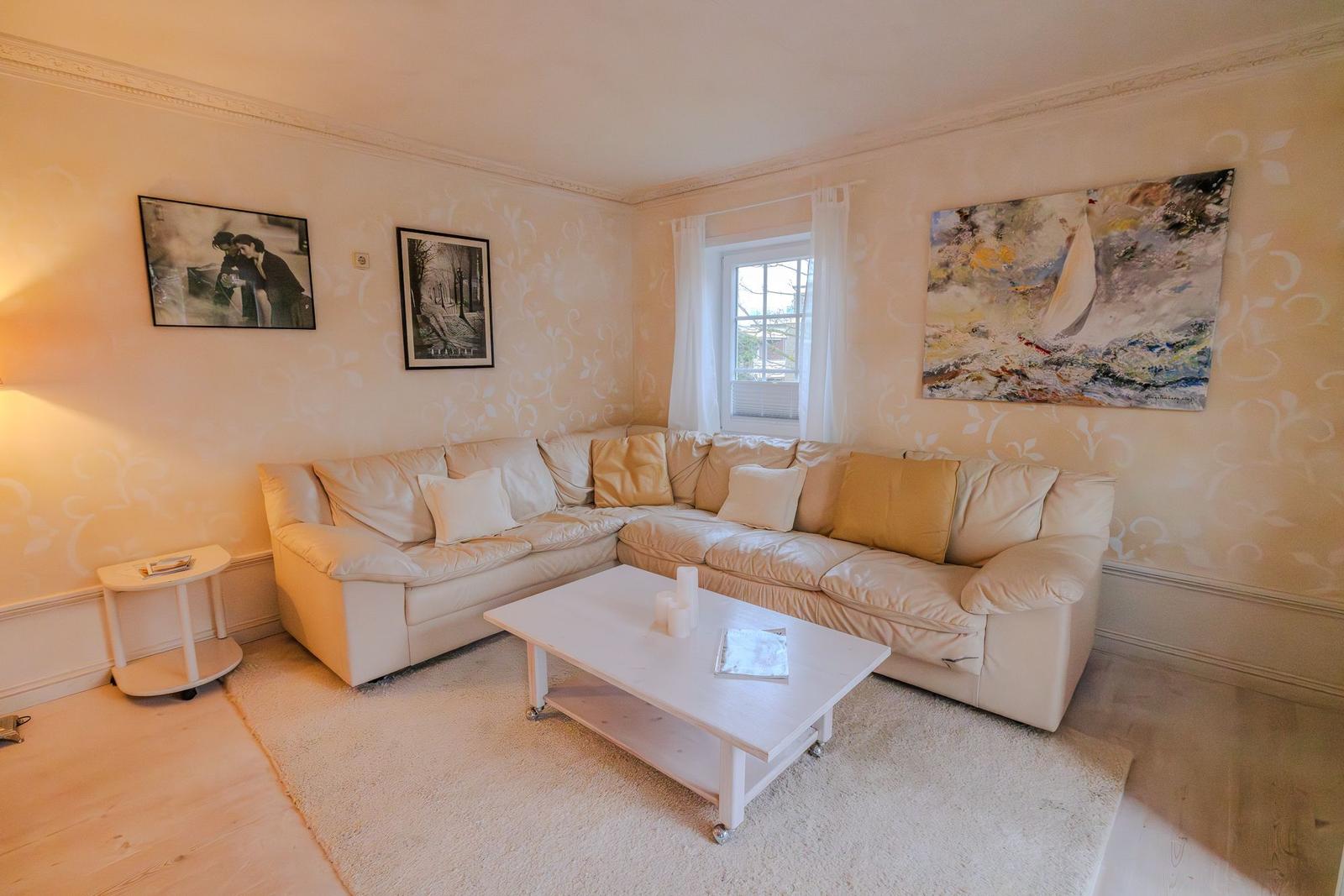 Wohnzimmer mit Ecksofa, Couchtisch und Wandbildern.