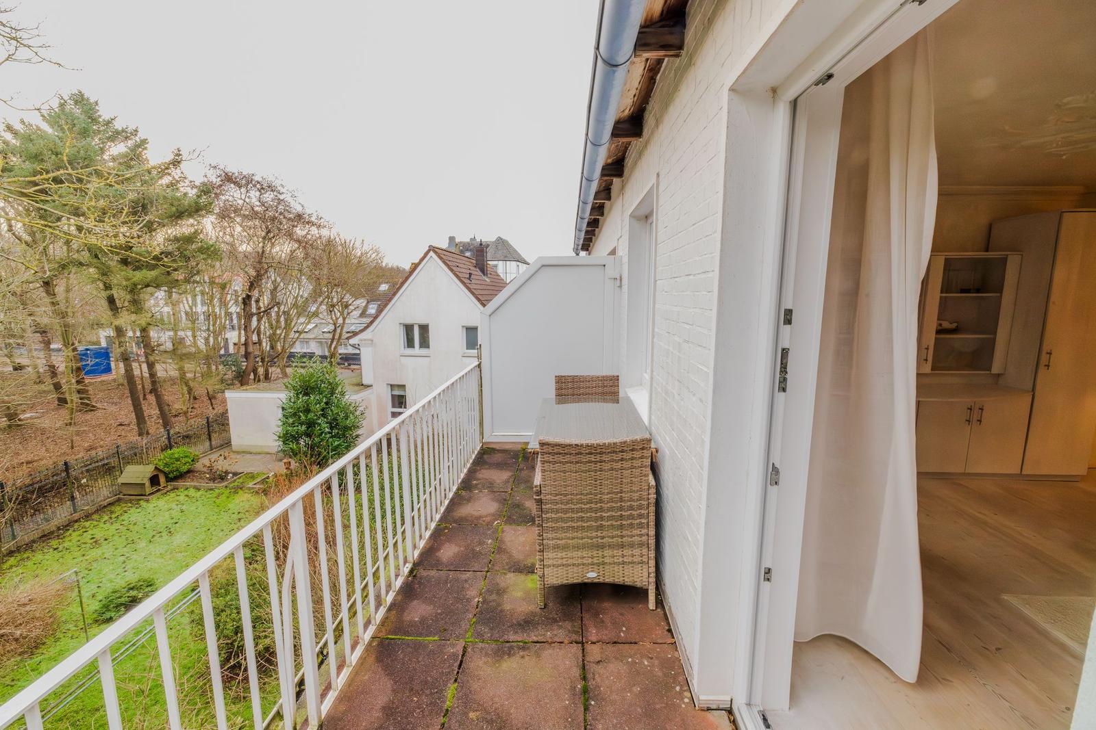 Terrasse mit Gartenblick und Sitzgruppe, Tür führt ins Innere.