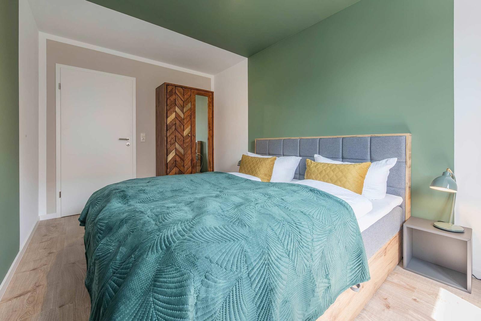 Schlafzimmer mit Bett, Nachttisch und Kleiderschrank.