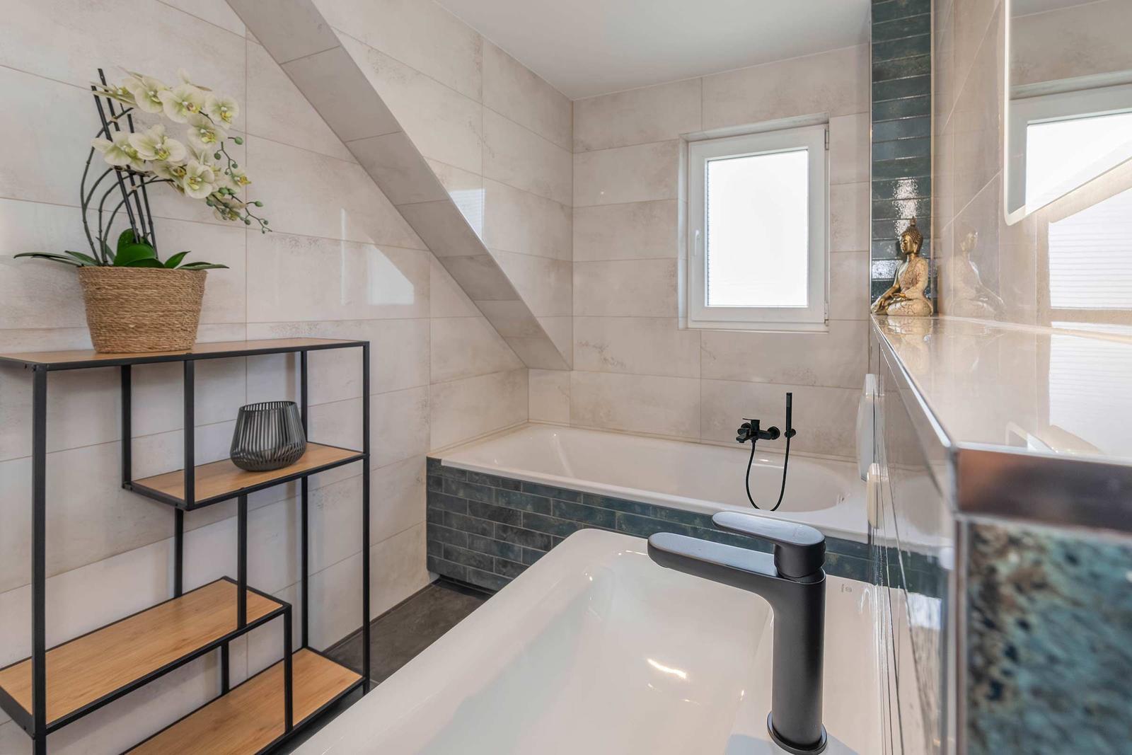 Bad mit Badewanne, Waschbecken und Fenster unter Dachschräge.
