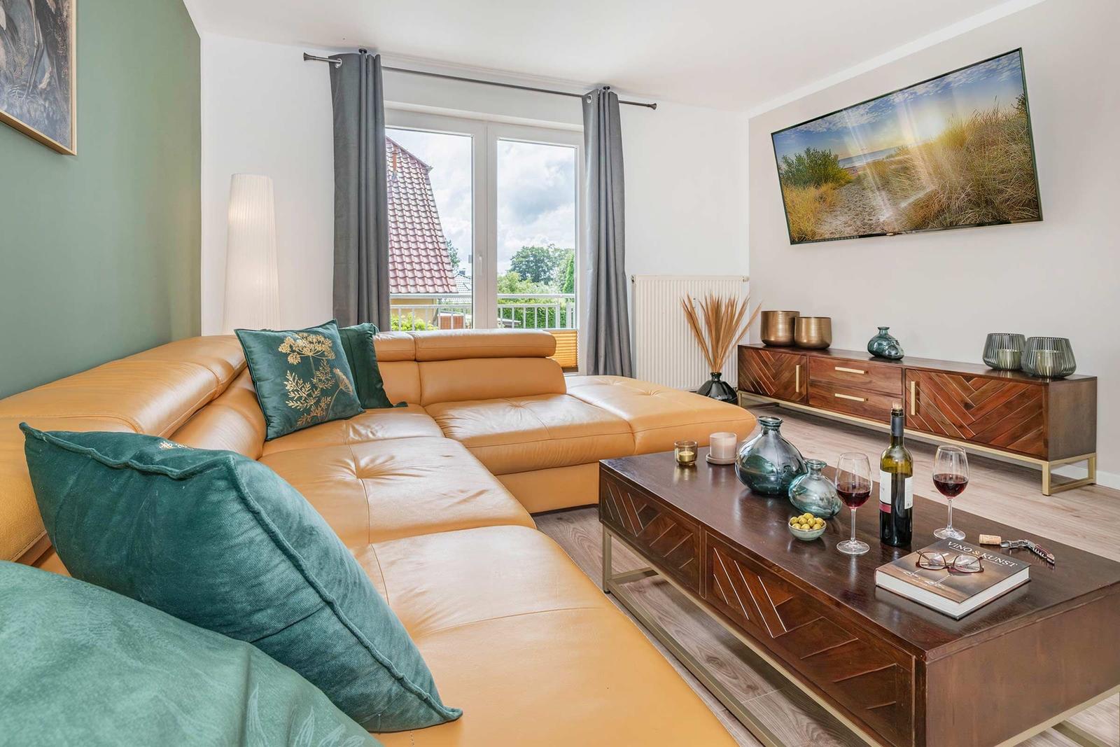 Ein Wohnzimmer mit braunem Sofa, Holztisch und Fernseher an der Wand.