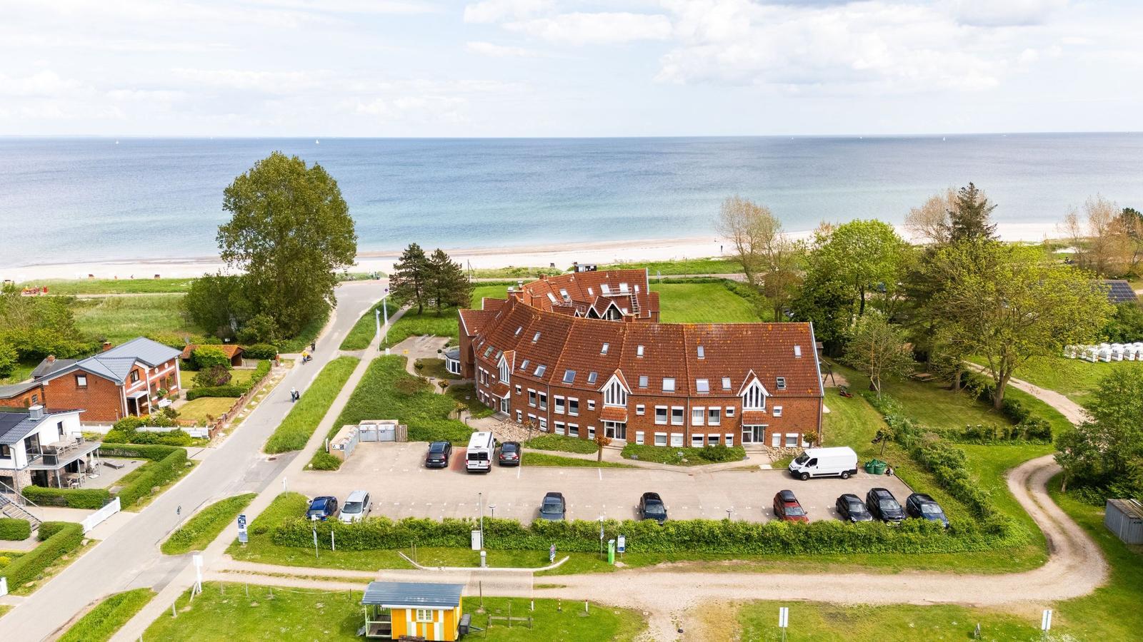 Rotes Gebäude mit Parkplatz neben Strand und Meer.