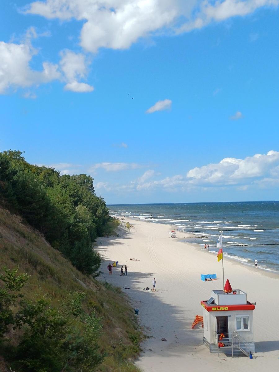 Strand mit Rettungswache, Sandstrand, Meer und bewölktem Himmel.