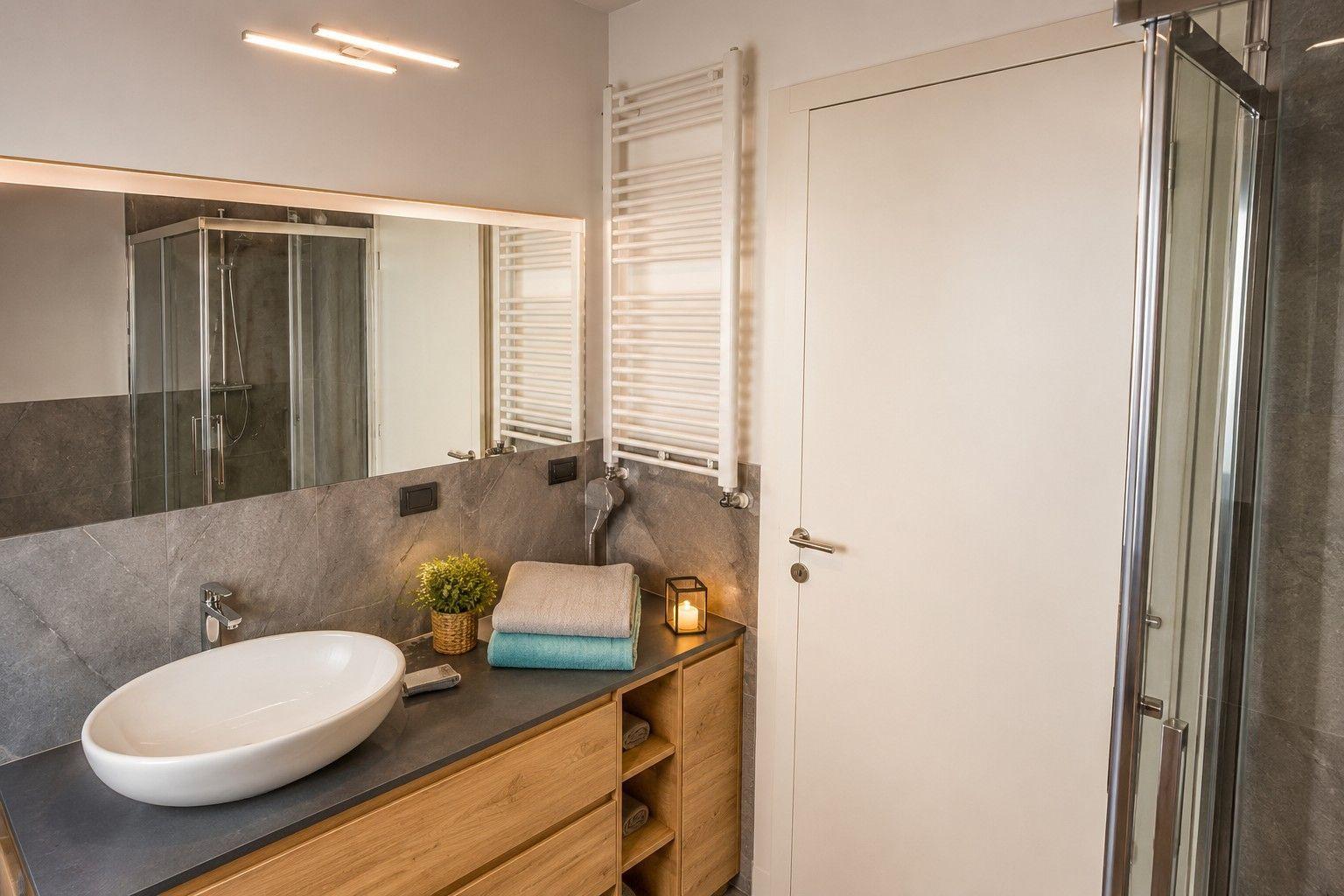 Badezimmer mit Waschbecken, Dusche und Handtuchheizung.