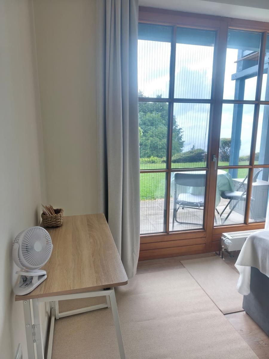 Schreibtisch mit Ventilator und Blick auf Terrasse