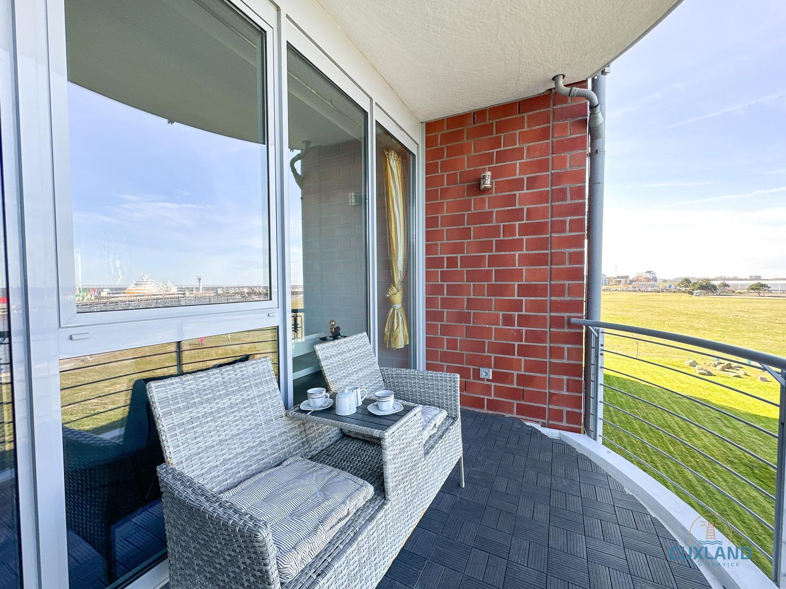 Terrasse mit Sitzgruppe und Blick auf Grünfläche und Hafen