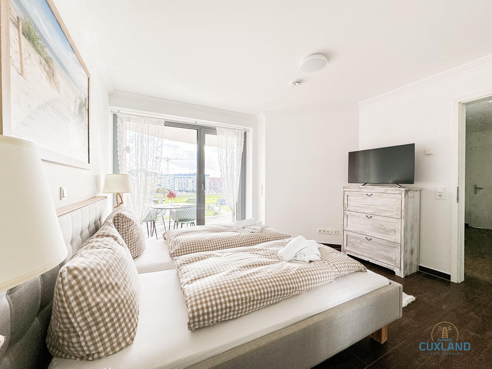 Schlafzimmer mit Doppelbett, Balkon und Fernseher.
