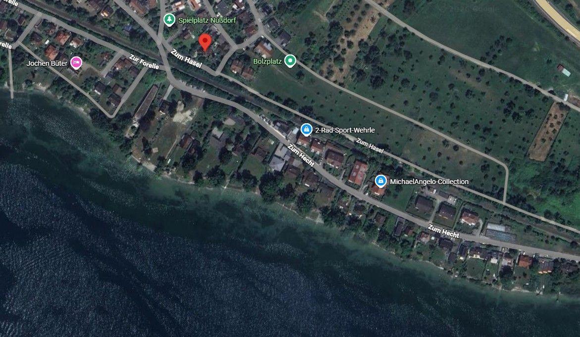 Satellitenbild zeigt Küstenlage mit Straßen und Grünflächen. Standort markiert.