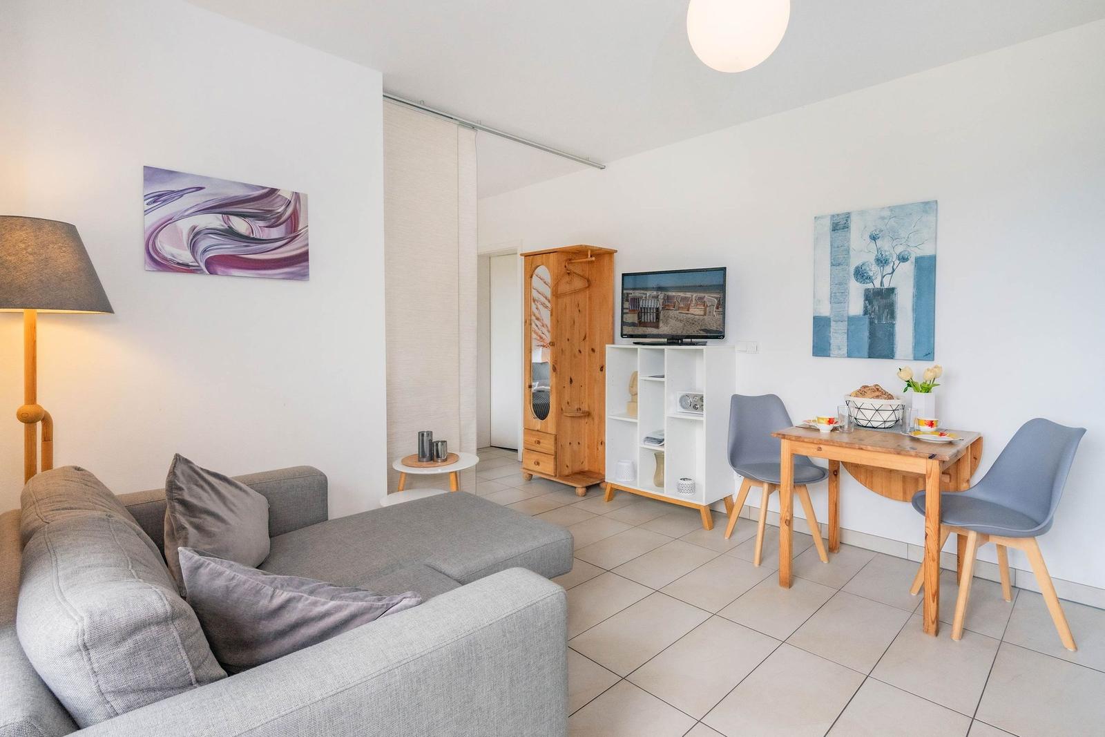 Wohn- und Essbereich mit Sofa, Tisch, Stühlen und Fernseher.
