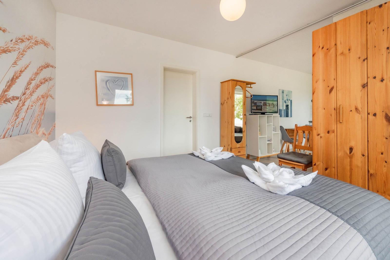 Ein Schlafzimmer mit Bett, Kleiderschrank und Fernseher.