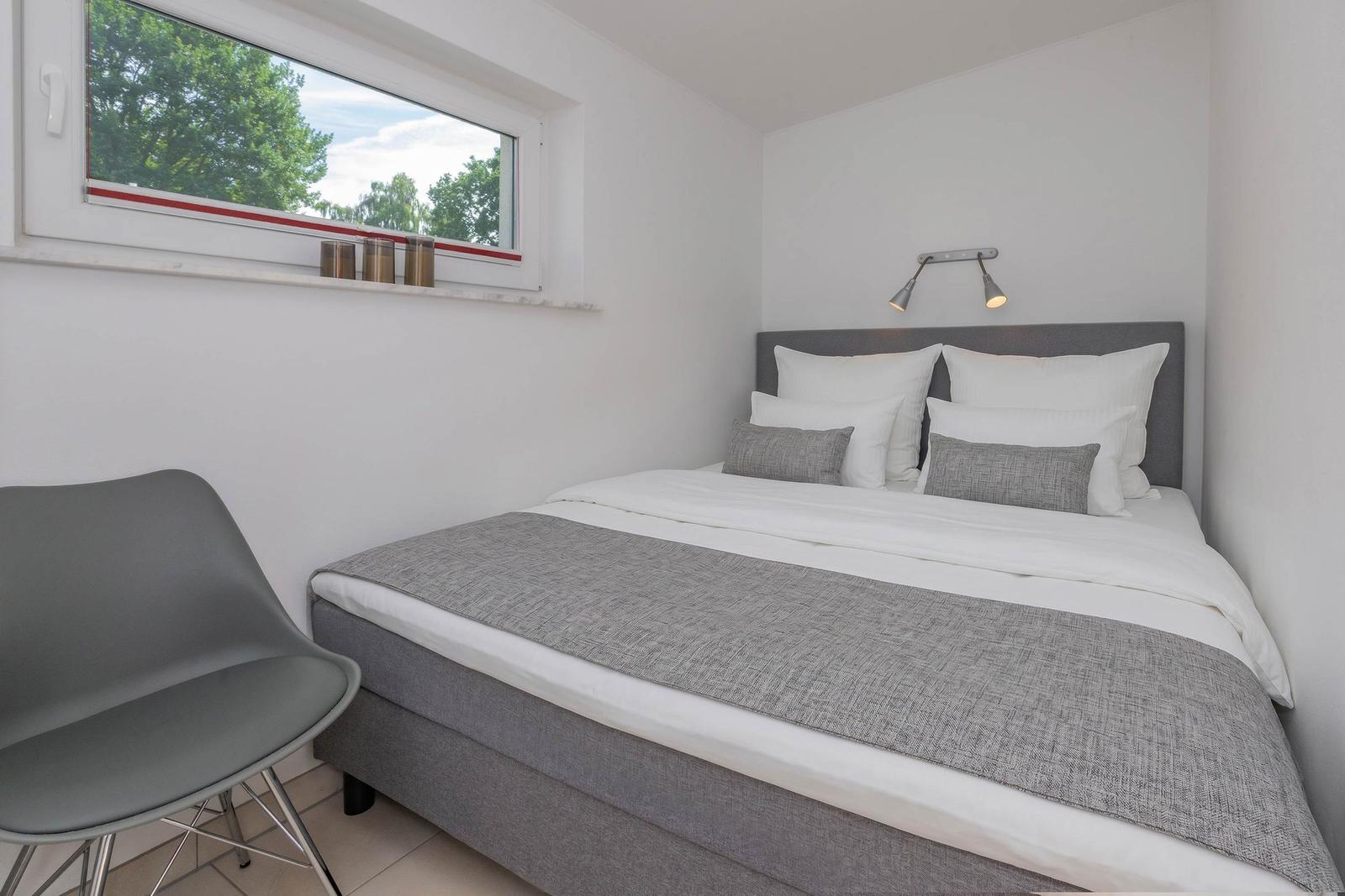 Schlafzimmer mit Bett, Fenster und Stuhl