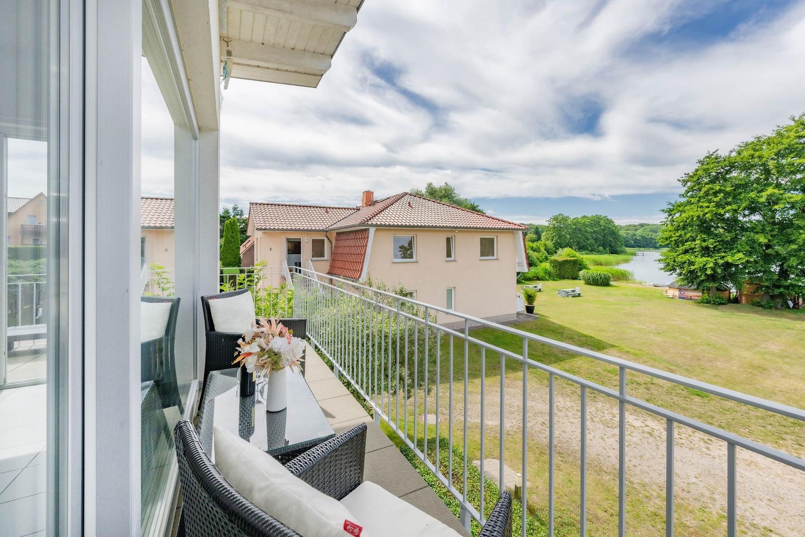 Terrasse mit Sitzgelegenheiten und Blick auf Haus und Grünfläche.