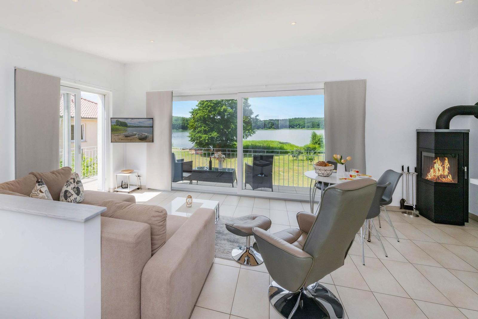 Wohn- und Essbereich mit Kamin, Terrasse und Blick auf einen See.