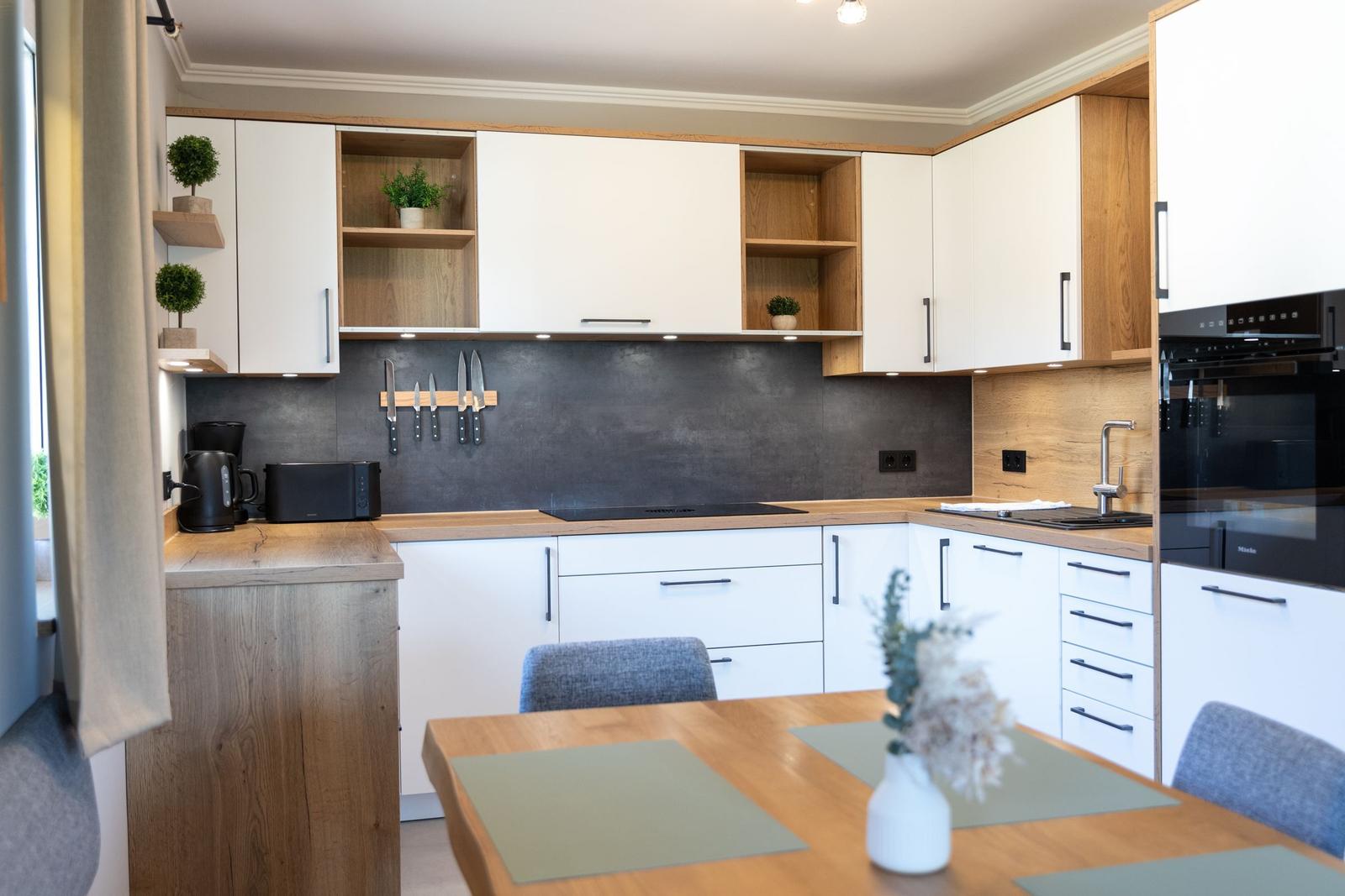 Moderne Küche mit Holz- und Weißfronten, Arbeitsplatte und Essbereich.