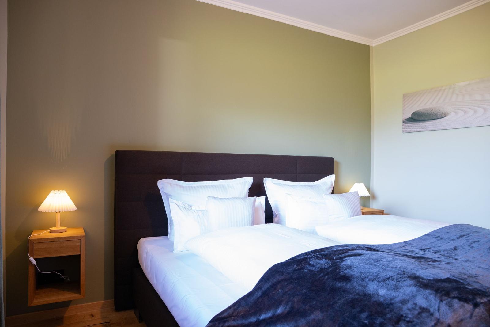 Schlafzimmer mit Doppelbett, Nachttischen und Wandbild.