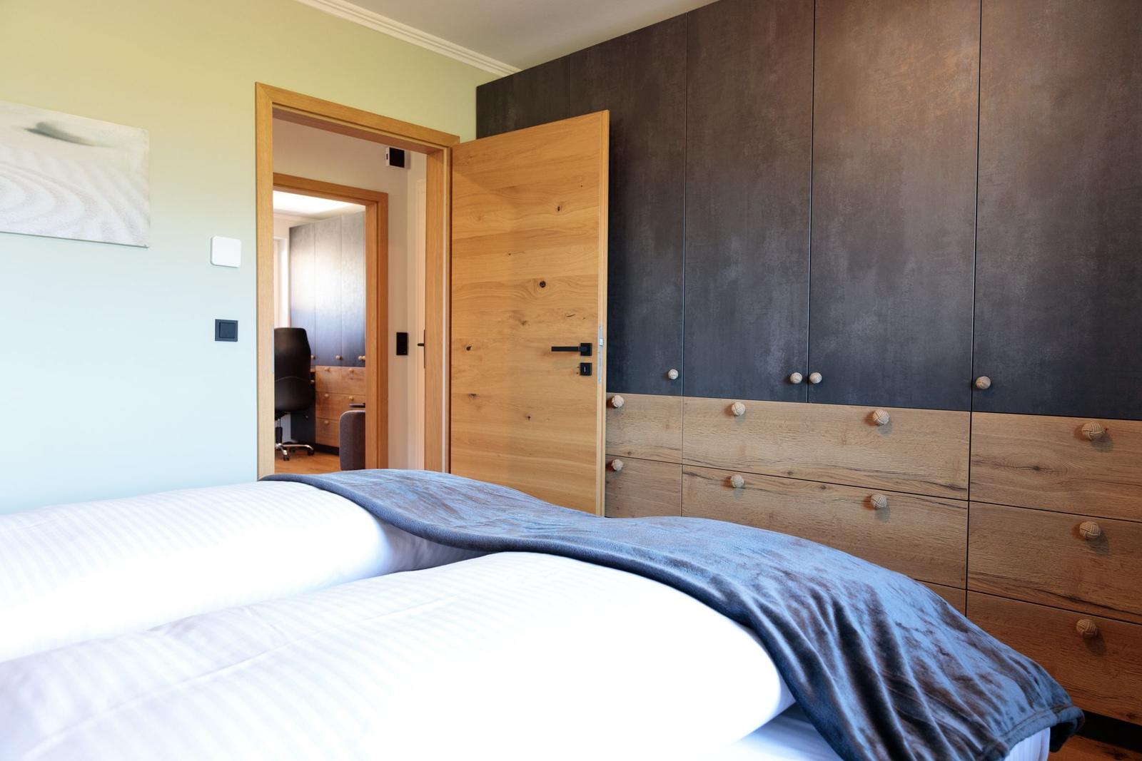 Schlafzimmer mit Bett, Kleiderschrank und Tür zum Arbeitszimmer.