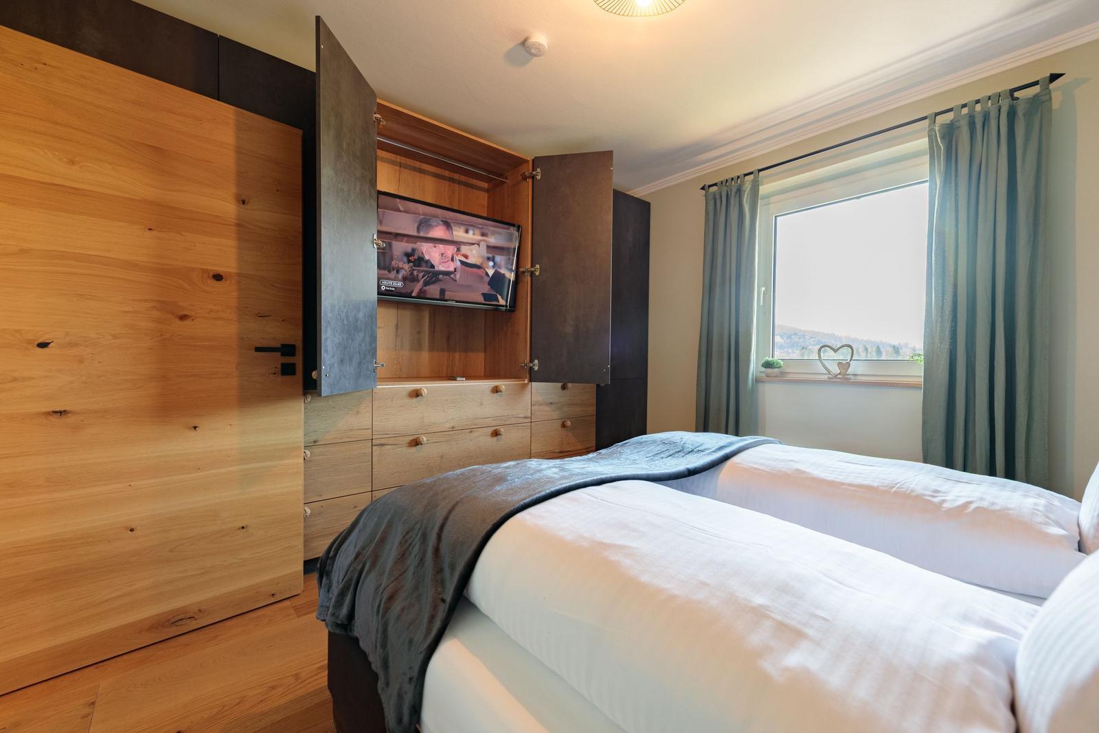 Schlafzimmer mit Doppelbett, integriertem Fernseher und Fenster mit Blick.