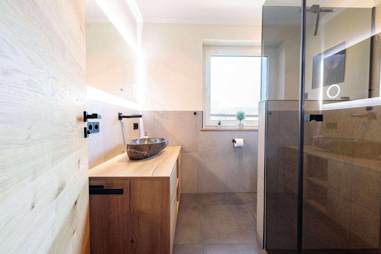 Bad mit Holzwaschtisch, Dusche und Fenster