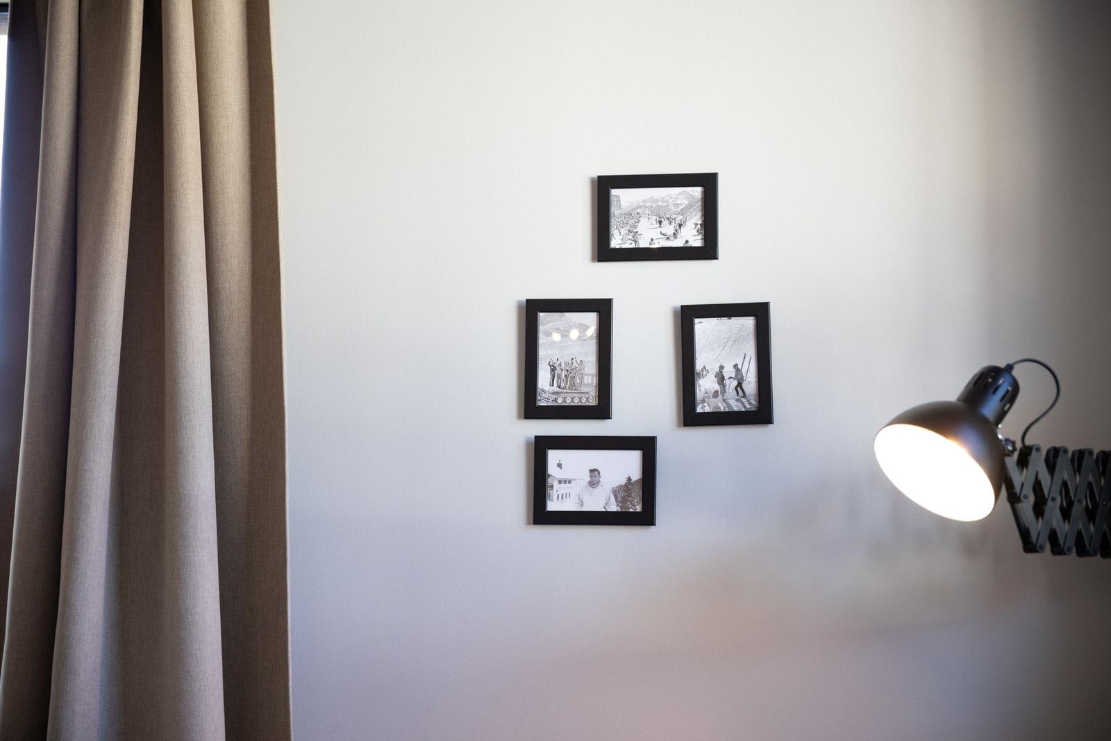 Wand mit vier schwarz-weißen Bildern und einer Lampe.