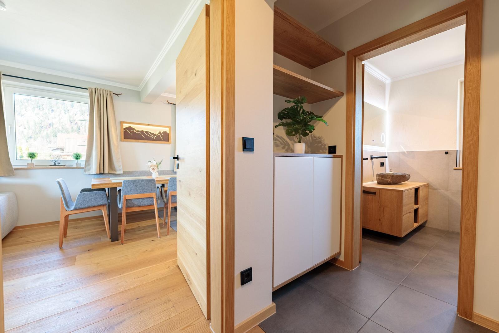 Eingangsbereich mit Blick in Wohn- und Badezimmer. Holzboden und moderne Einrichtung.