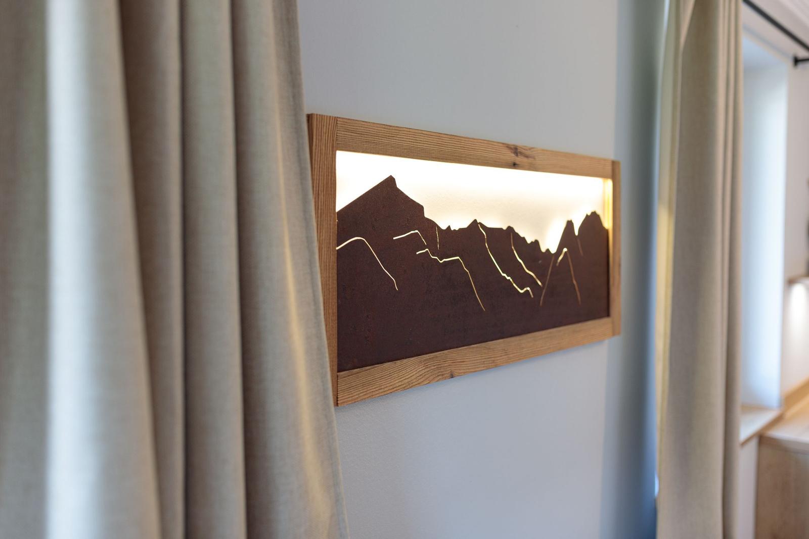 Hölzernes Wandbild mit Bergsilhouette und eingebauter Beleuchtung an der Wand.