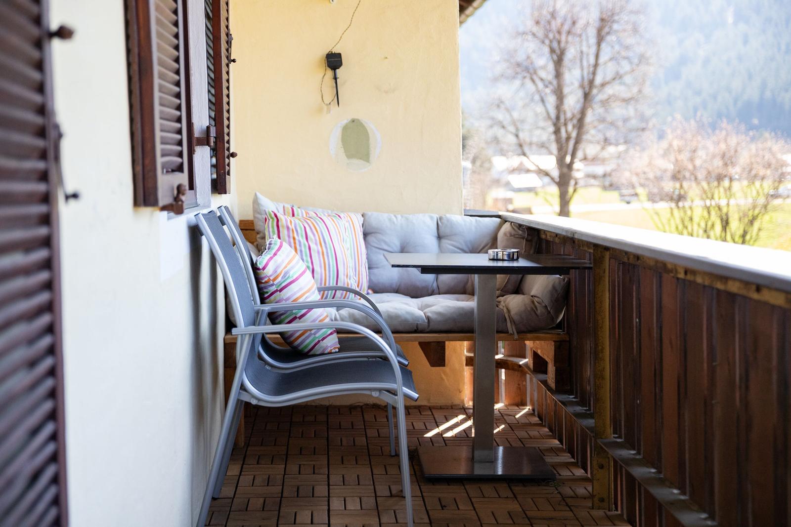 Terrasse mit Sitzbank, Tisch und Stühlen. Blick auf grüne Landschaft.