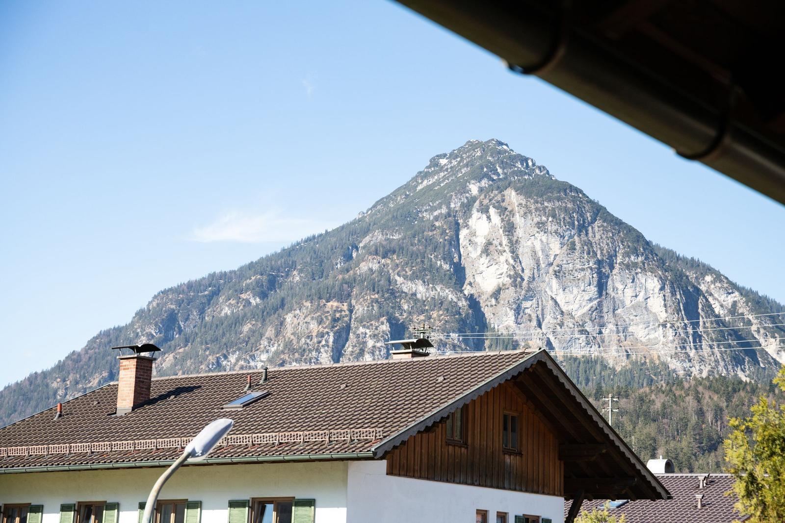 Von der Terrasse bietet sich ein Blick auf einen Berg mit Felsen und Wald.