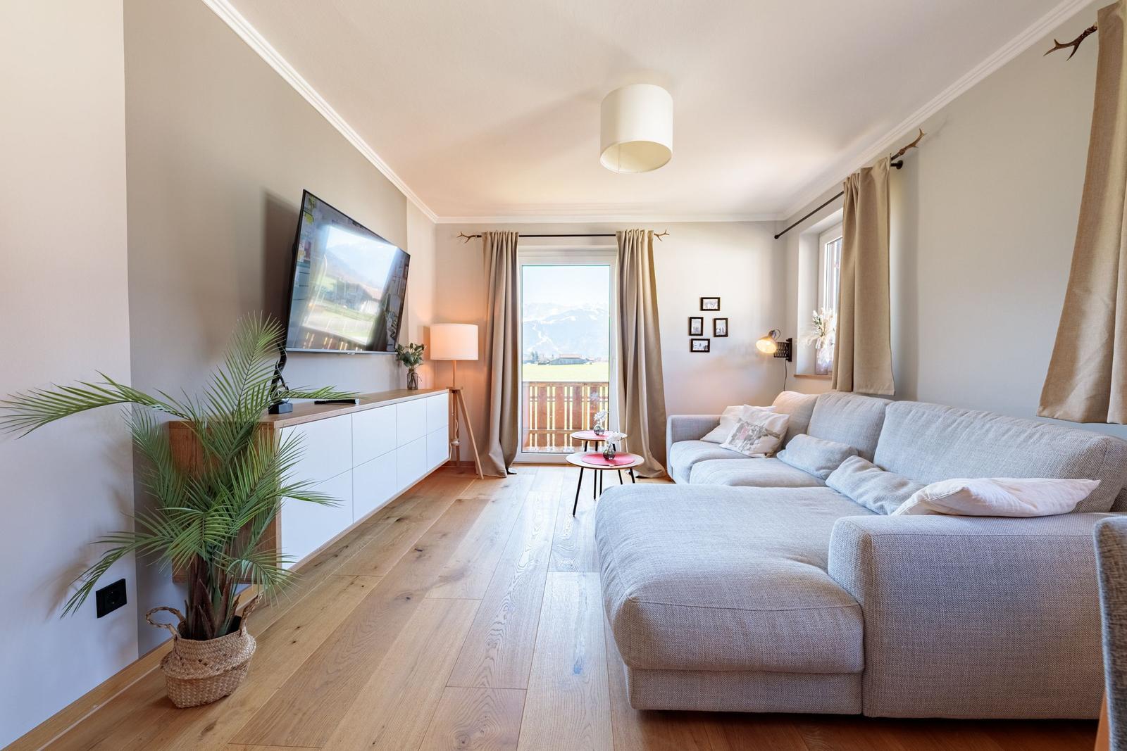 Wohnzimmer mit Sofa, TV und Balkonblick.