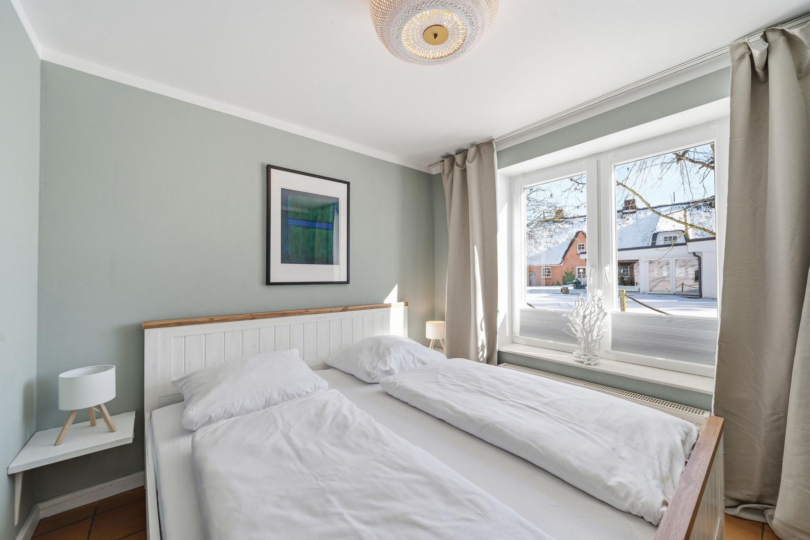 Schlafzimmer mit Doppelbett, Fenster und Wandbild.