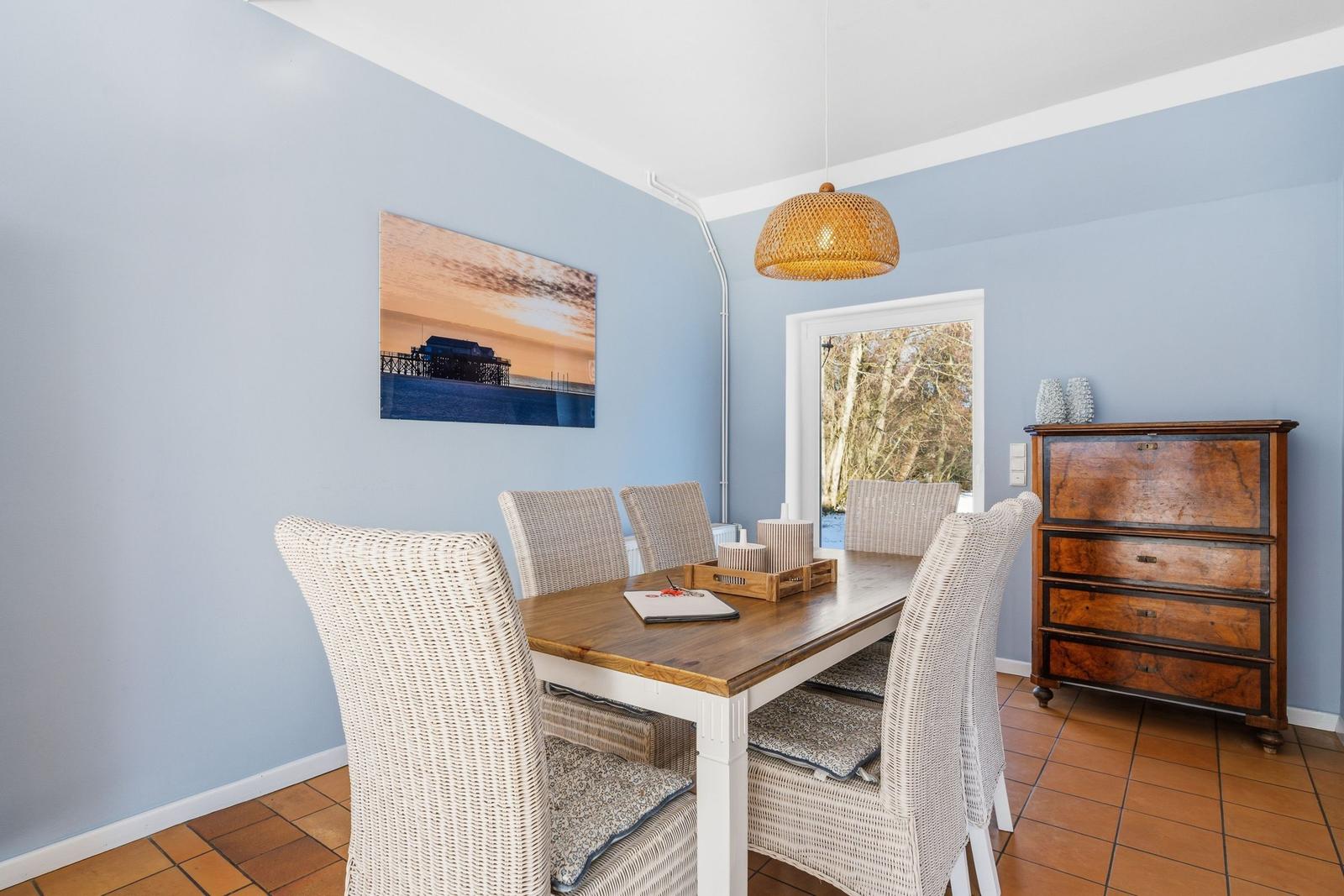 Esszimmer mit Esstisch, Stühlen und Wandbild. Holzfußboden und antiker Schrank.