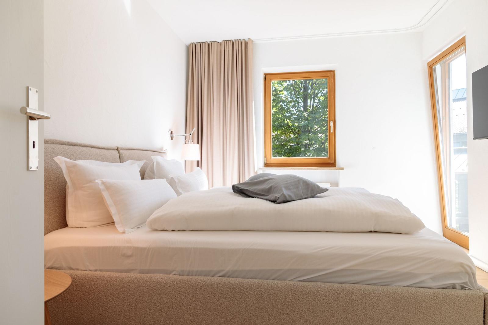 Ein Schlafzimmer mit Bett, Fenster und Vorhängen.
