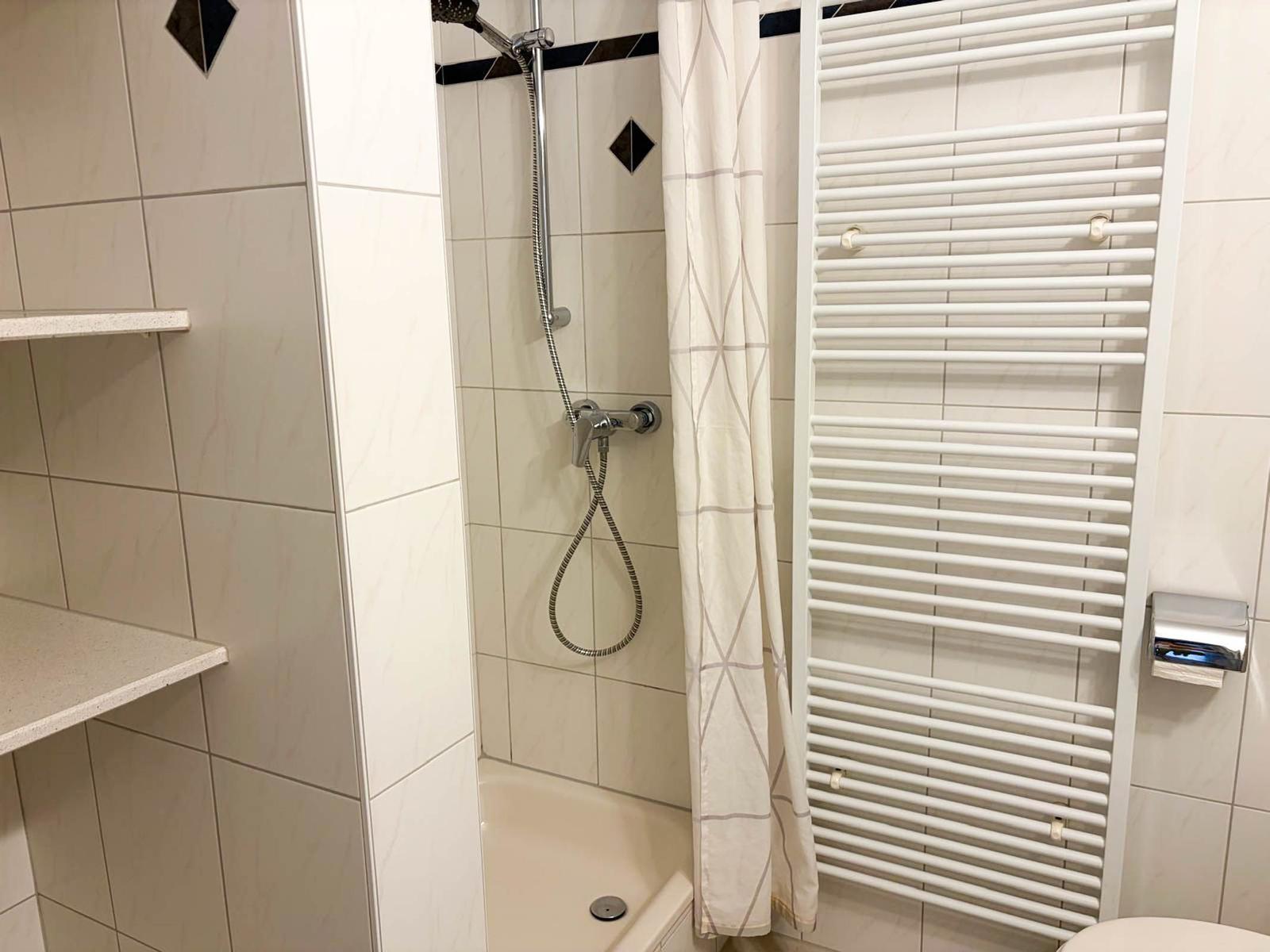 Dusche mit Duschbrause, Handtuchhalter und Wandregal