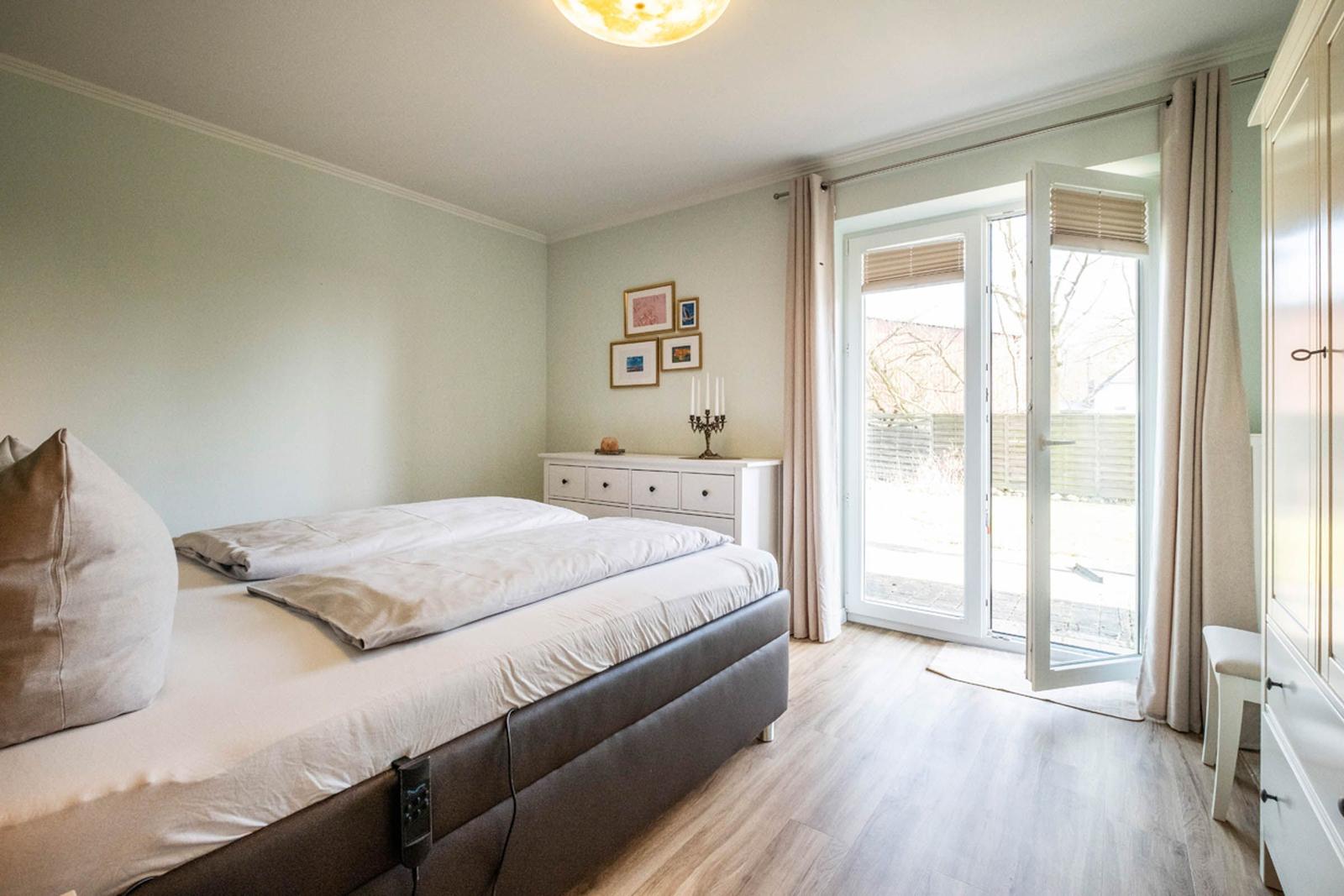 Schlafzimmer mit Doppelbett, Schrank und Glastür zum Außenbereich.