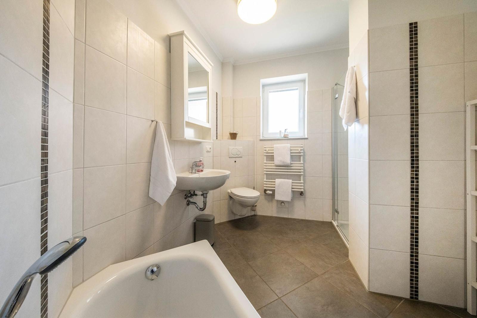 Badezimmer mit Badewanne, Dusche, Toilette und Waschbecken.