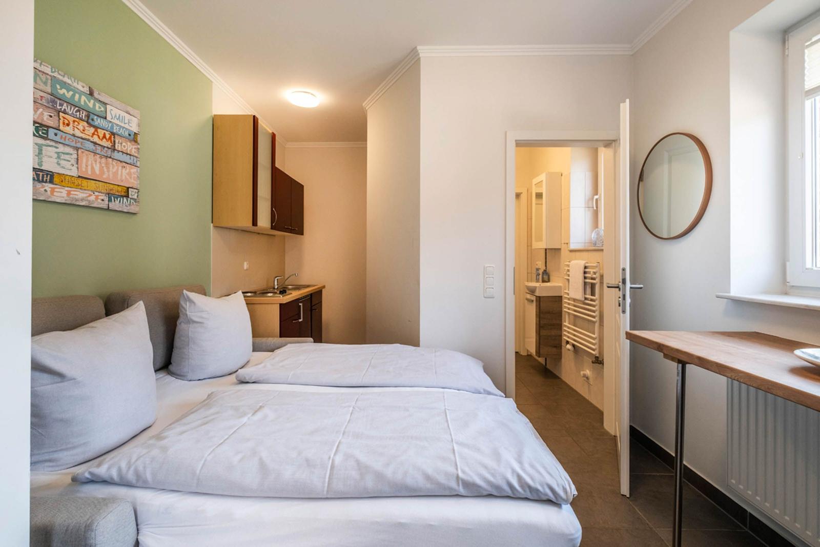 Schlafzimmer mit Bett, Küchenzeile und angrenzendem Bad.